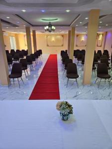 a large room with a red carpet and chairs at Hotel Gabu Karsa in Gabú