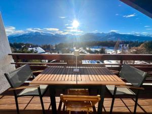 a wooden table and chairs on a balcony with mountains at Attique de la Moubra 4 in Crans-Montana