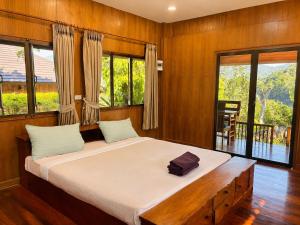 a bedroom with a large bed in a room with windows at Aruna Mountain Lodge in Ban Huai Rin +27 photos