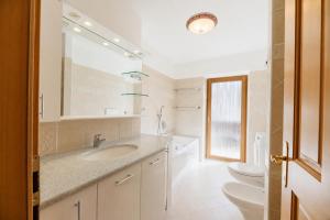 a white bathroom with a sink and a toilet at Appartamenti Cèsa Sorèie by AMA Val di Fassa in Canazei +34 photos