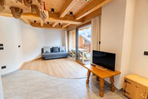 a living room with a tv and a table at Appartamenti Cèsa Sorèie by AMA Val di Fassa in Canazei