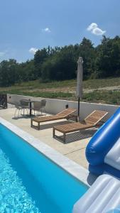 a pool with chairs and an umbrella next to a swimming pool at SoL Zlatni koreni in Palanka +37 photos