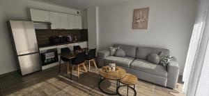 a living room with a couch and tables and a kitchen at L'escalade Lyon Aéroport in Janneyrias