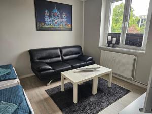 a living room with a black leather couch and a table at Apartment mea in Berlin