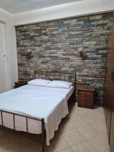 a bedroom with a bed and a brick wall at Kohil Guest House in Ksamil
