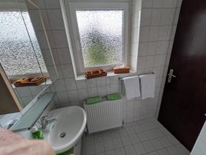 a white bathroom with a sink and a window at Haus Kiel Wohnung Wolfswarte in Altenau +5 photos