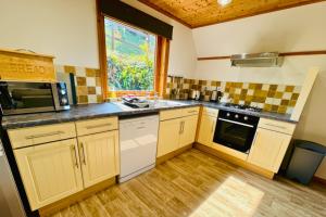 a kitchen with yellow cabinets and a window at Lazy Bear Lodge with Hot Tub - Finlake Resort and Spa in Devon in Chudleigh