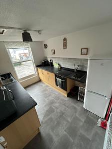 a kitchen with a black counter top and a white refrigerator at Boho Bliss in Swansea