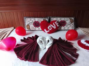 a bed with two hearts and valentines pillows and balloons at Devilmountain kabana Kalupahana in Bandarawela