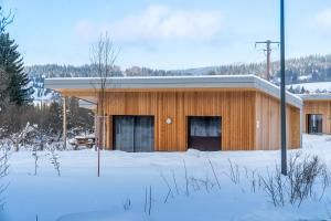 a wooden building in the snow with trees in the background at Ô Doubs Chalets in Mouthe