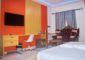 a bedroom with a bed and a chair and a television at Hotel St Flavien Lomé in Taméklo