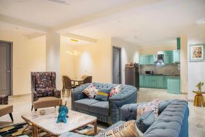 a living room with blue couches and a kitchen at Dream Haven Kasauli in Kasauli