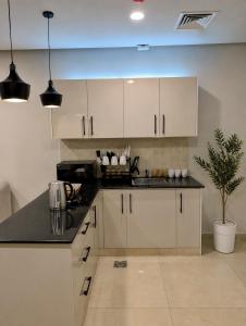 a kitchen with white cabinets and a potted plant at The Vista 1BR by Winchester in Mall of Islamabad F-7 Margalla & City Views in Islamabad +16 photos