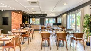 a restaurant with tables and chairs in a room with windows at Campanile NATURE - Moulins Avermes in Avermes