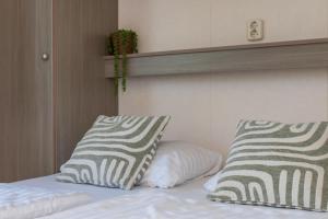 a bedroom with a bed with two pillows on it at Chalet dichtbij strand Vrouwenpolder in Serooskerke +17 photos