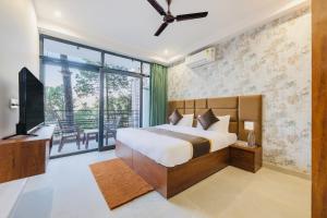a bedroom with a bed and a tv and a balcony at Dream Haven Kasauli in Kasauli