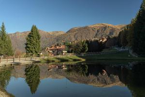 a lake with a house and mountains in the background at Albergo Legazzuolo Montecampione in Artogne