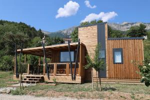 a wooden house with a porch and mountains in the background at Valterra Lodges à Châtillon-en-Diois in Châtillon-en-Diois
