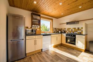 a kitchen with wooden floors and a stainless steel refrigerator at Lazy Bear Lodge with Hot Tub - Finlake Resort and Spa in Devon in Chudleigh