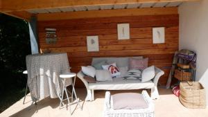 a porch with a couch and chairs on a patio at A l'orée du bois - Chambres d'hôtes in Hostun