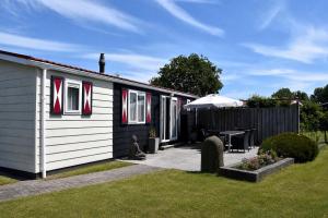 a small house with a patio and an umbrella at Chalet dichtbij strand Vrouwenpolder in Serooskerke