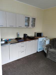 a kitchen with white cabinets and a sink and a refrigerator at SunKiss in Melnragė