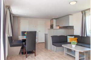 a living room with a couch and a table at Chalet dichtbij strand Vrouwenpolder in Serooskerke