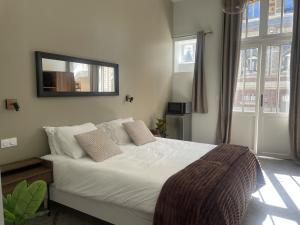 a bedroom with a white bed with a mirror on the wall at Les Thibériades in Martin-Église