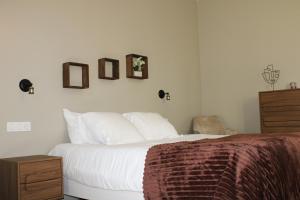 a bedroom with a bed with white sheets and a dresser at Les Thibériades in Martin-Église