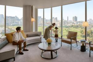 a family standing in a living room with a woman at Waldorf Astoria Bangkok in Bangkok