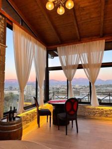 a room with a table and chairs and large windows at Vila Shehi Guesthouse and Winery in Tirana +8 photos