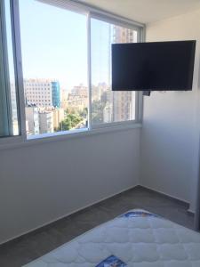 a bedroom with a flat screen tv on a wall with windows at Dizengoff 24A in Netanya