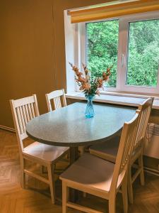 a dining room table with chairs and a vase with flowers at Pargi apartment 2 in Viljandi