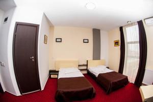 two beds in a room with red carpet at GP Hotel StarCity in Tătărani
