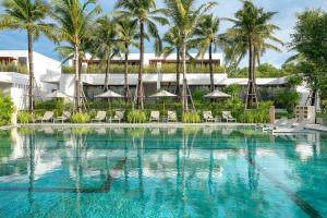 a swimming pool with chairs and palm trees in front of a building at Meliá Phuket Mai Khao in Mai Khao Beach