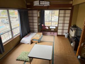 a small room with a table and a room with windows at Miyoshiya Ryokan in Tanabe