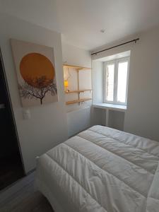 a white bedroom with a bed and a window at Le Nid d'Ouilly in Pont-d'Ouilly