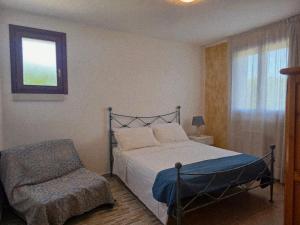 a bedroom with a bed and a chair and a window at Villa Kepos in Arnesano