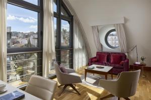 a living room with a red couch and chairs and large windows at NH Collection Vigo in Vigo