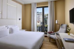 a hotel room with a bed and a desk and a window at NH Collection Vigo in Vigo