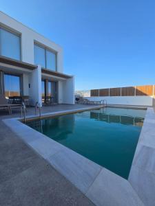a swimming pool in front of a house at Divina Loft C Modern Loft with Shared Pool in Perivolia