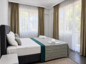 a bedroom with a large bed with windows at Kagan Holiday Apartments in Kemer