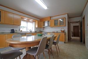 a kitchen with a wooden table and chairs and a table at Caramulo Valley View in Campo de Besteiros