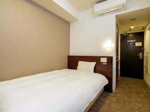 a bedroom with a large white bed and a door at Dormy Inn Takamatsu in Takamatsu