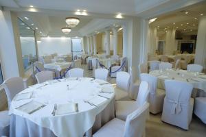 a banquet room with white tables and white chairs at Hellenia Yachting Hotel & SPA in Giardini Naxos