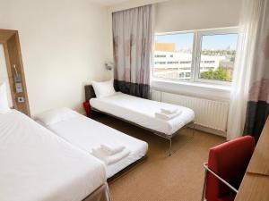ein Hotelzimmer mit zwei Betten und einem Fenster in der Unterkunft Novotel The Hague World Forum in Den Haag