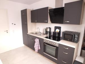 a kitchen with black cabinets and a microwave at Komfort-Ferienwohnung gierskopp.pur in Olsberg +16 photos