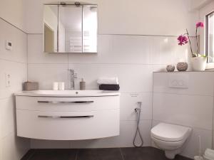 a white bathroom with a toilet and a sink at Komfort-Ferienwohnung gierskopp.pur in Olsberg