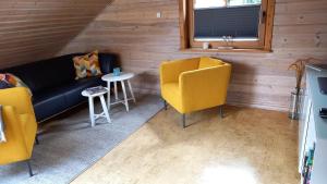 a living room with yellow chairs and a couch at FeWo Wardersee in Rohlsdorf
