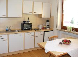 una cucina con armadi bianchi, tavolo e forno a microonde di Villa Malus a Castelbello